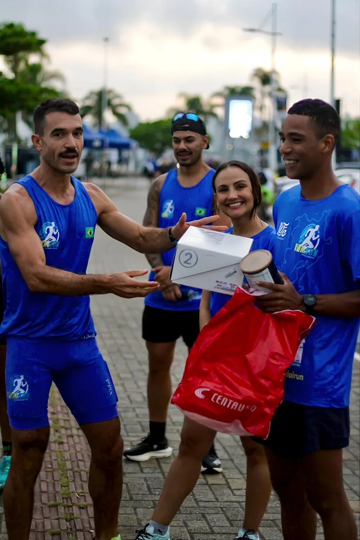Izaias Vidal entregando um prêmio a um aluno sorridente, com outros atletas da equipe ao redor